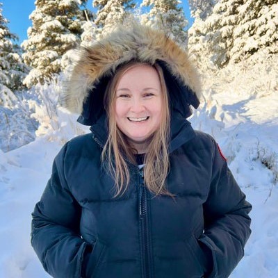 Esther smiling while wearing a navy jacket in the snow.