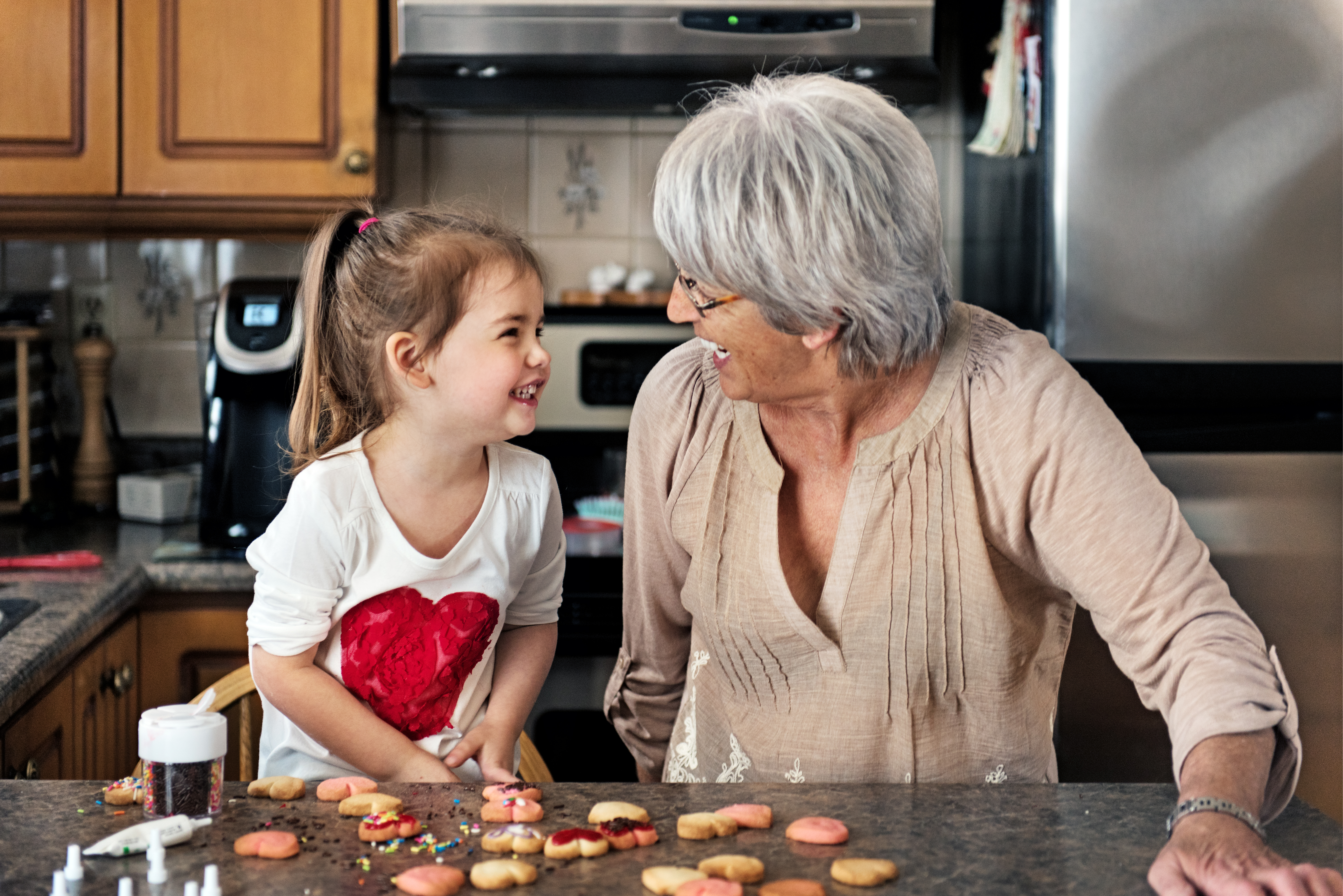 Grandmother and granddaughter with Valentines Day cookies at the kitchen counter.