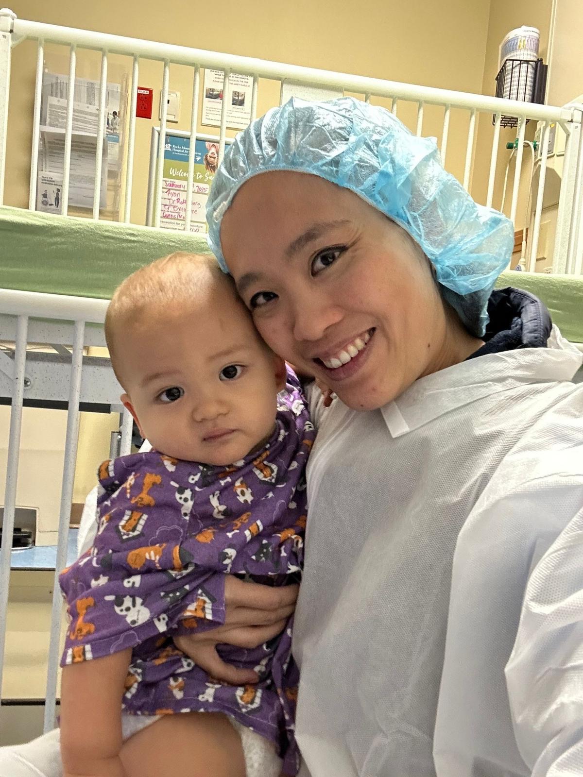 Shan Bundgaard in hospital scrubs smiling while holding her infant son Finn