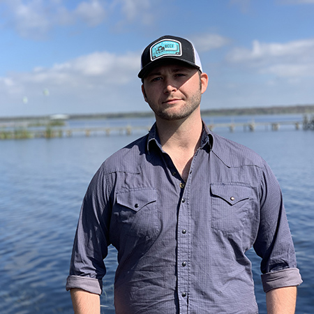 Eli McCoy posing in front of a lake