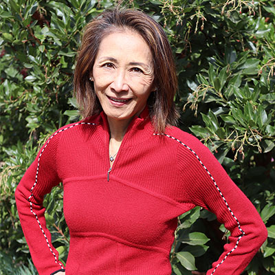 Aortic dissection survivor Dori Chiang smiles outdoors while wearing a red zip-up top.