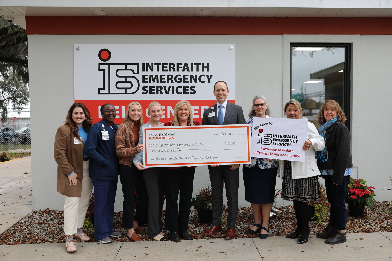A group of eight women and one man holding a large check made out for ten thousand dollars.