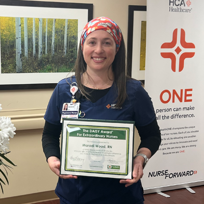 Marodi Wood smiling while holding her Daisy award of recognition.