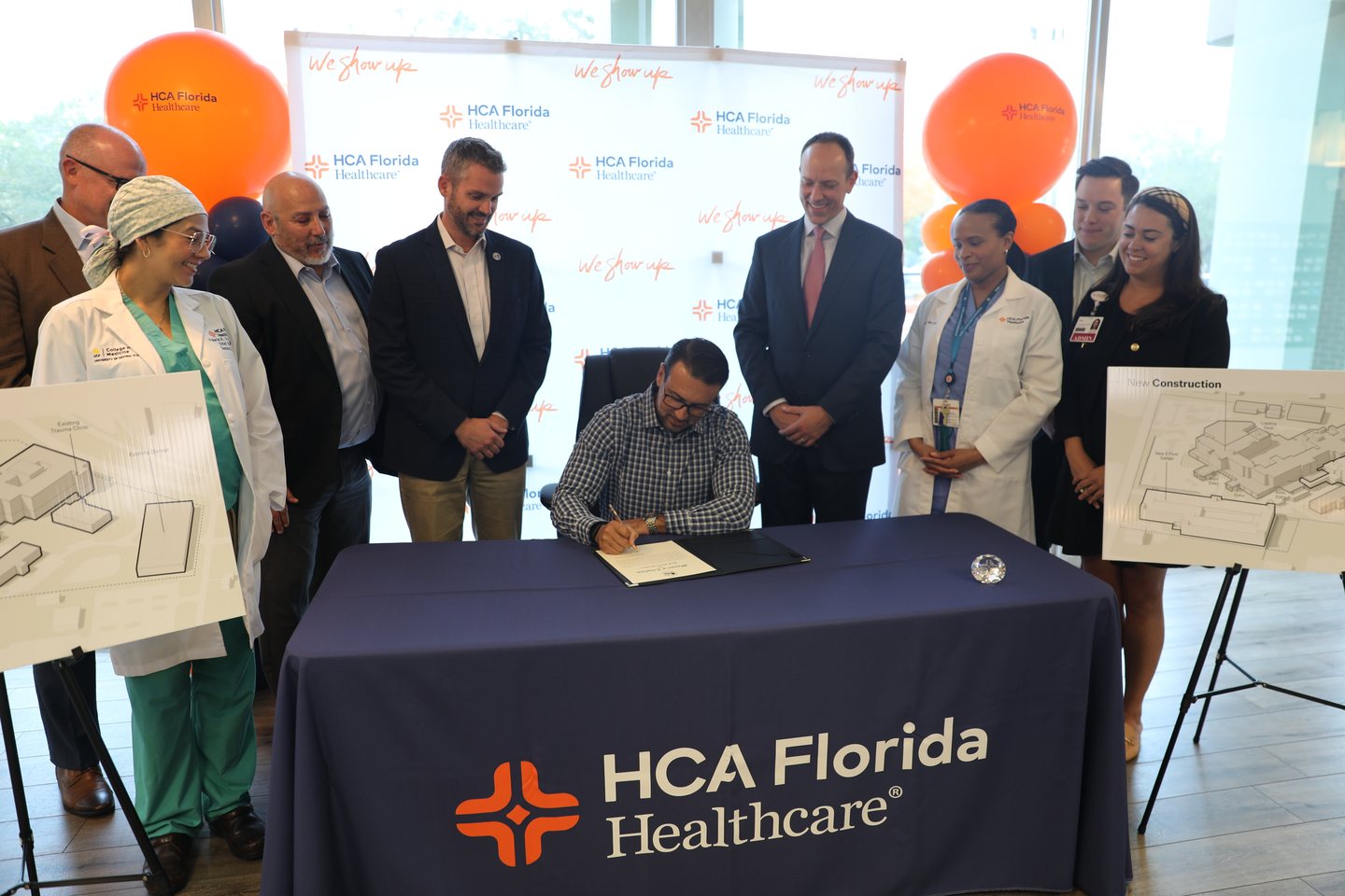 City, county and private officials smile as the mayor presents a document to the hospital leaders.