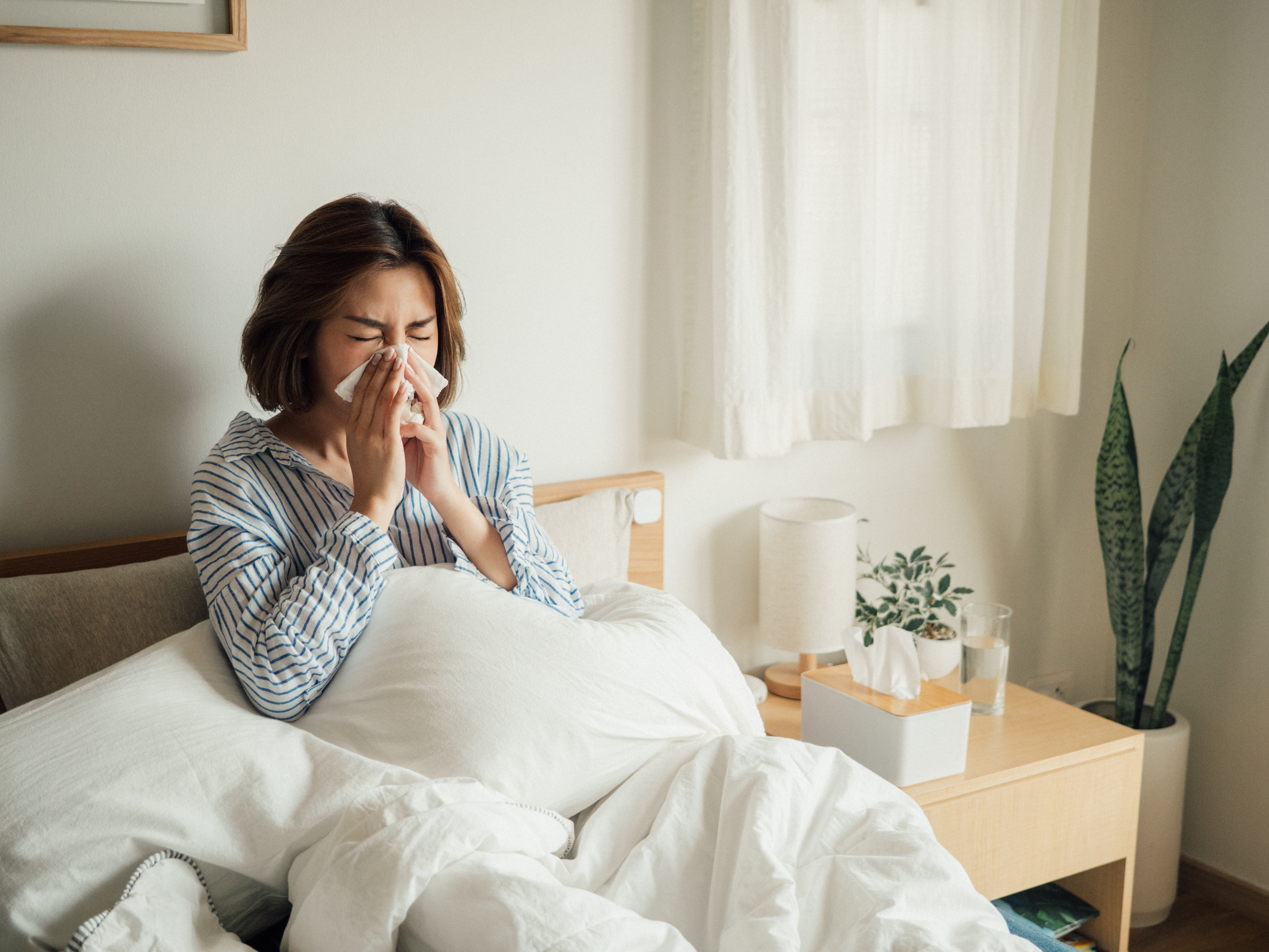 Woman blowing nose in bed.