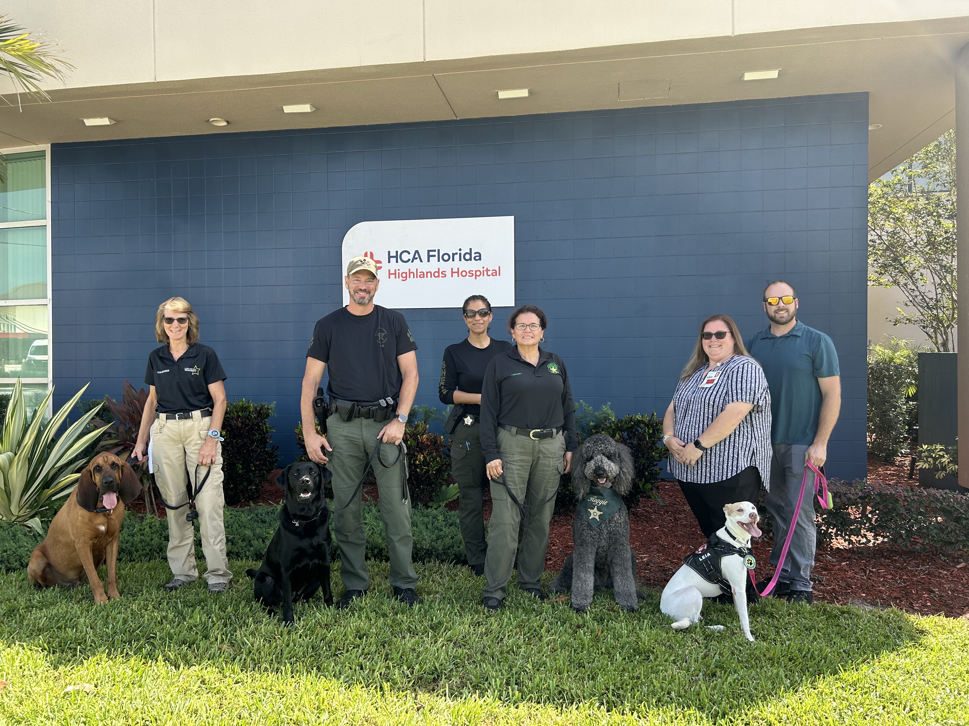 K-9 team members from various sheriff’s offices across the state of Florida and medical surgical manager Kimberly Goddard (striped top) pose for a picture with the therapy dogs outside of the hospital. 