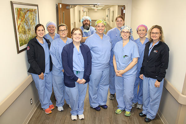 Staff of the Colleton Medical Center Surgical Services smiling while standing in the hospital hallway.