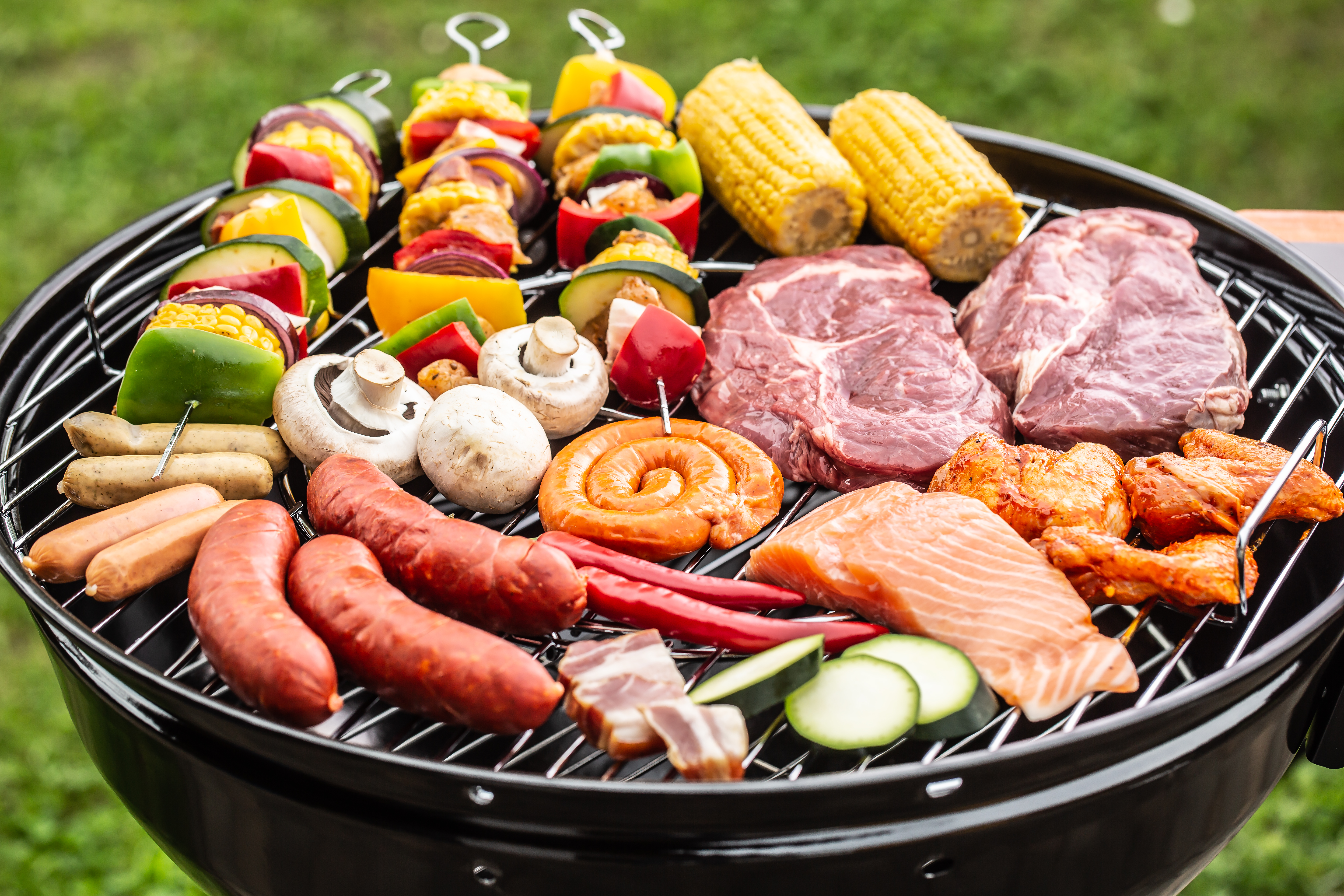 Assortment of foods on outdoor charcoal grill.