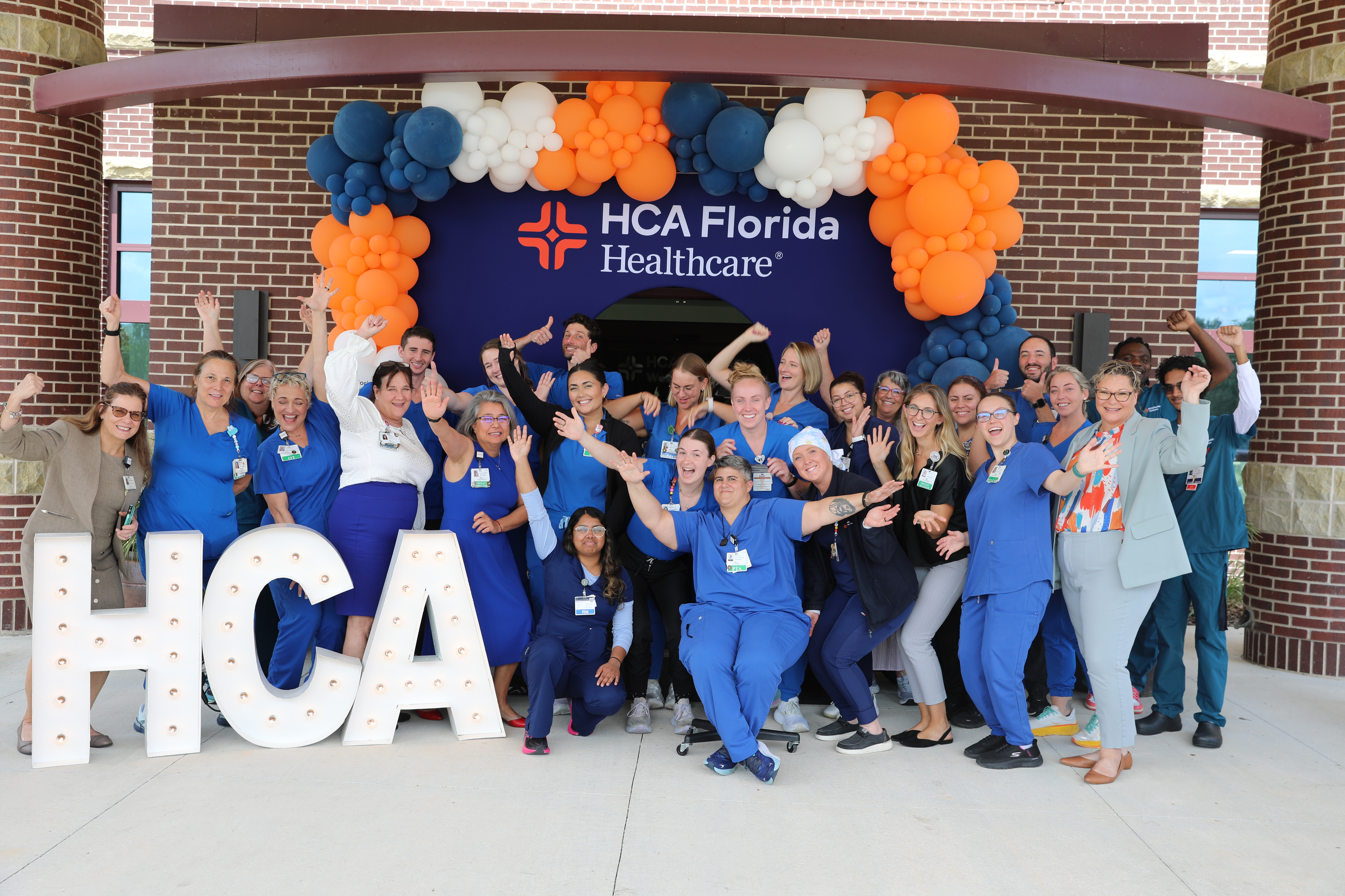Inpatient Rehabilitation Team at HCA Florida West Marion Hospital celebrate the opening of the new tower with HCA sign and blue/white/orange balloons