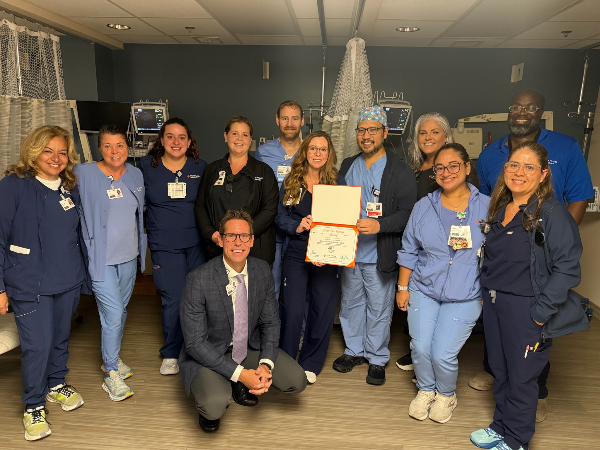 HCA Florida colleagues celebrate a care team award in a hospital room.