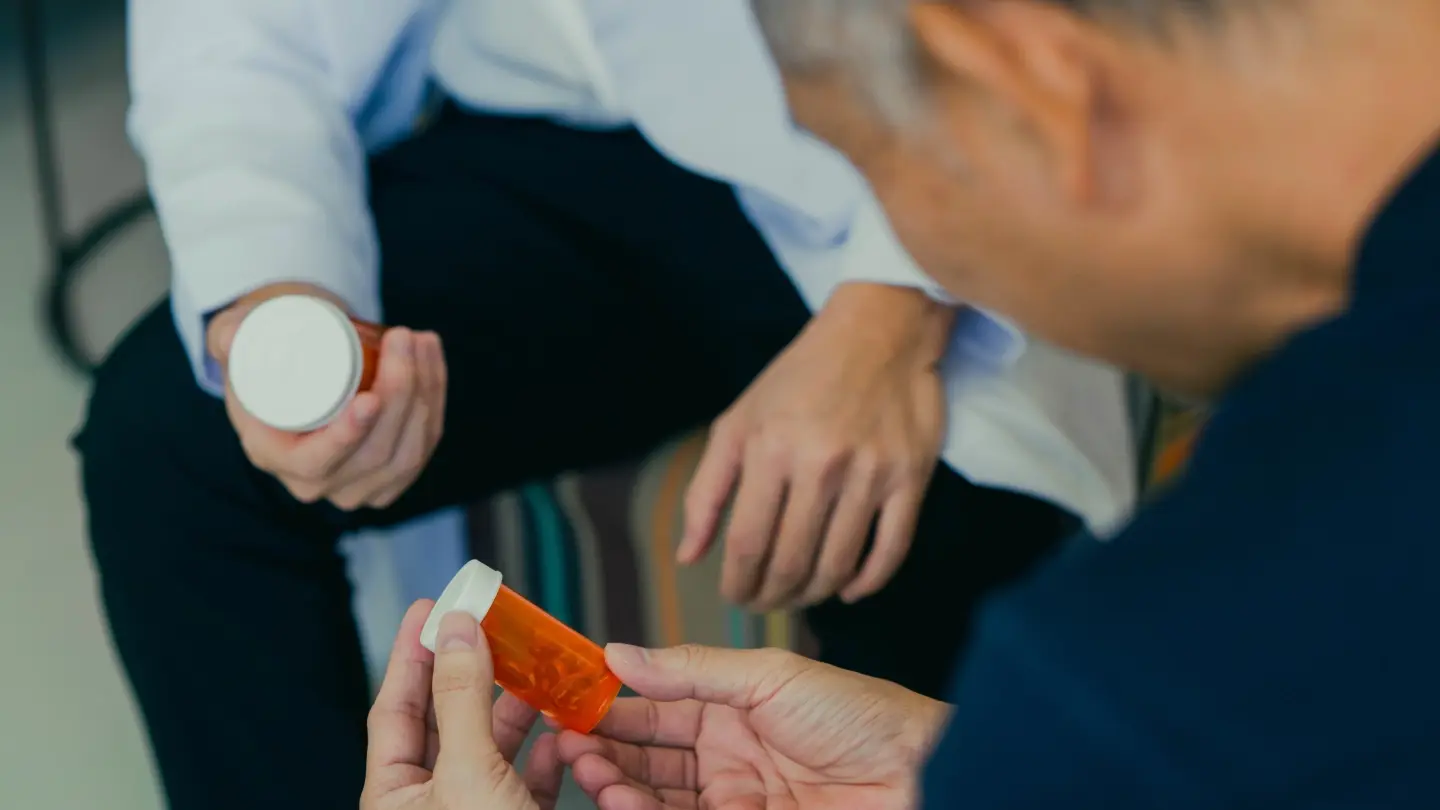 A senior man looking at a bottle of prescription pills.