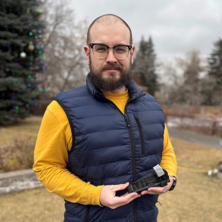 Stop The Bleed program participant Jake Allred holds a tourniquet while standing outdoors. 