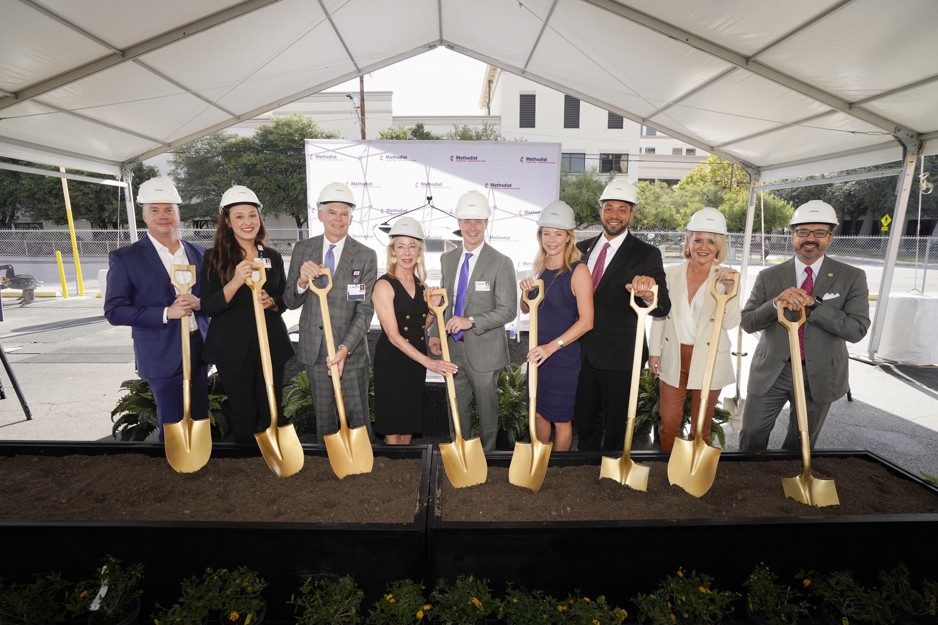 Metropolitan team members pose with helmets and golden shovels for ceremonial ground-breaking ceremony.