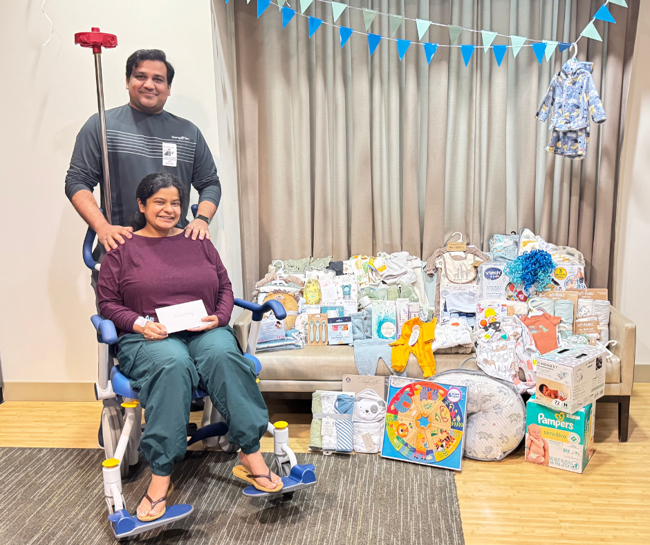 Image Shows: Man, woman, couple, wheel chair, room, curtains, baby clothes, various gifts for a baby, baby shower setting, party decorations, chair, rug