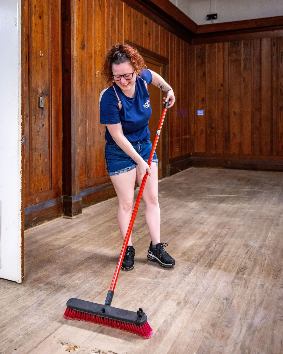 HCA Volunteer sweeping the floor.