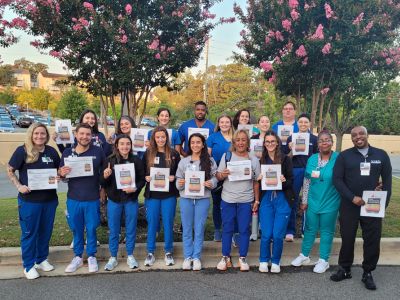 A large group of medical staff with each displaying their award certificate from the American Heart Association.