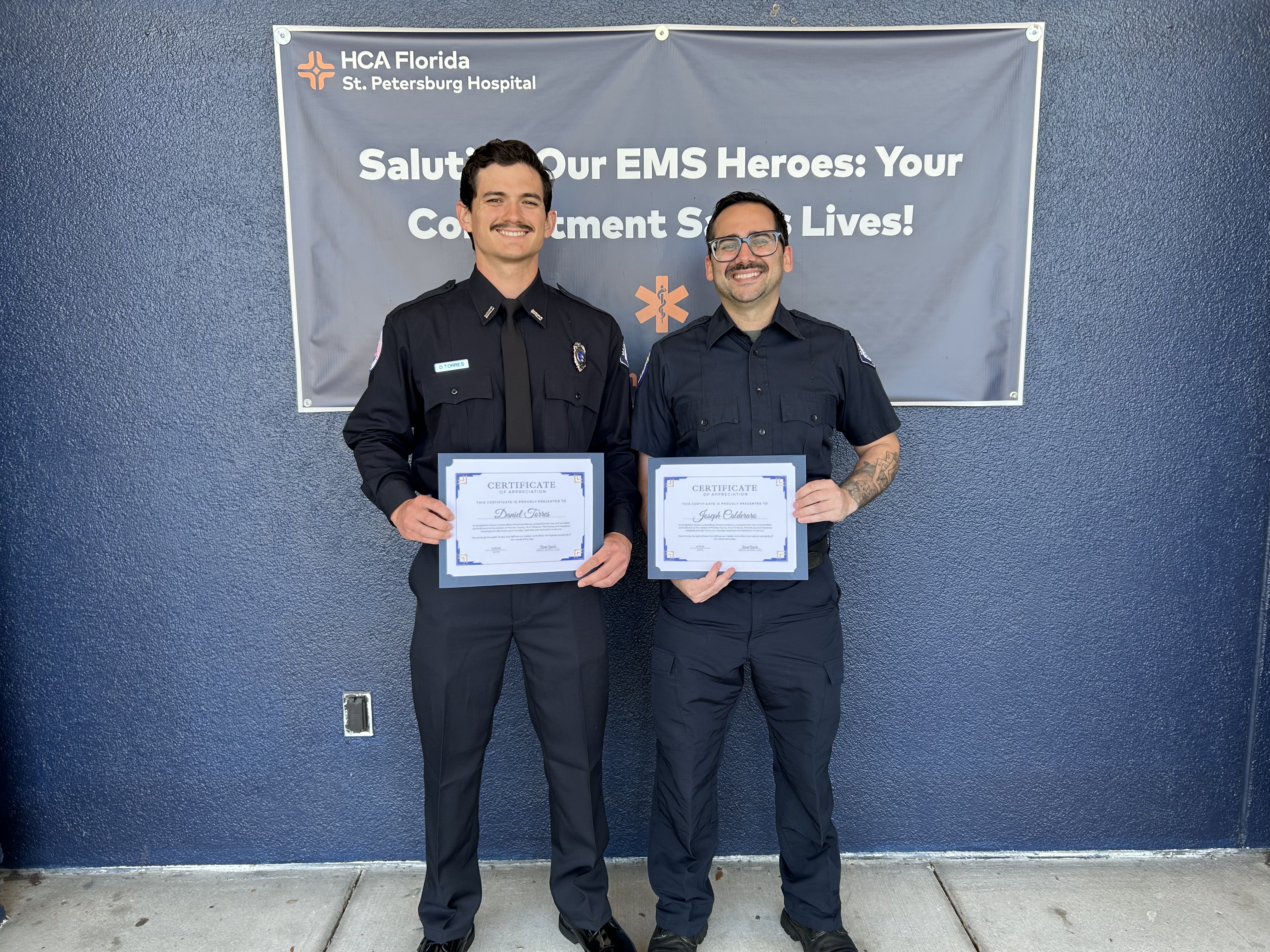 Two first responders holding their certificates proudly. 
