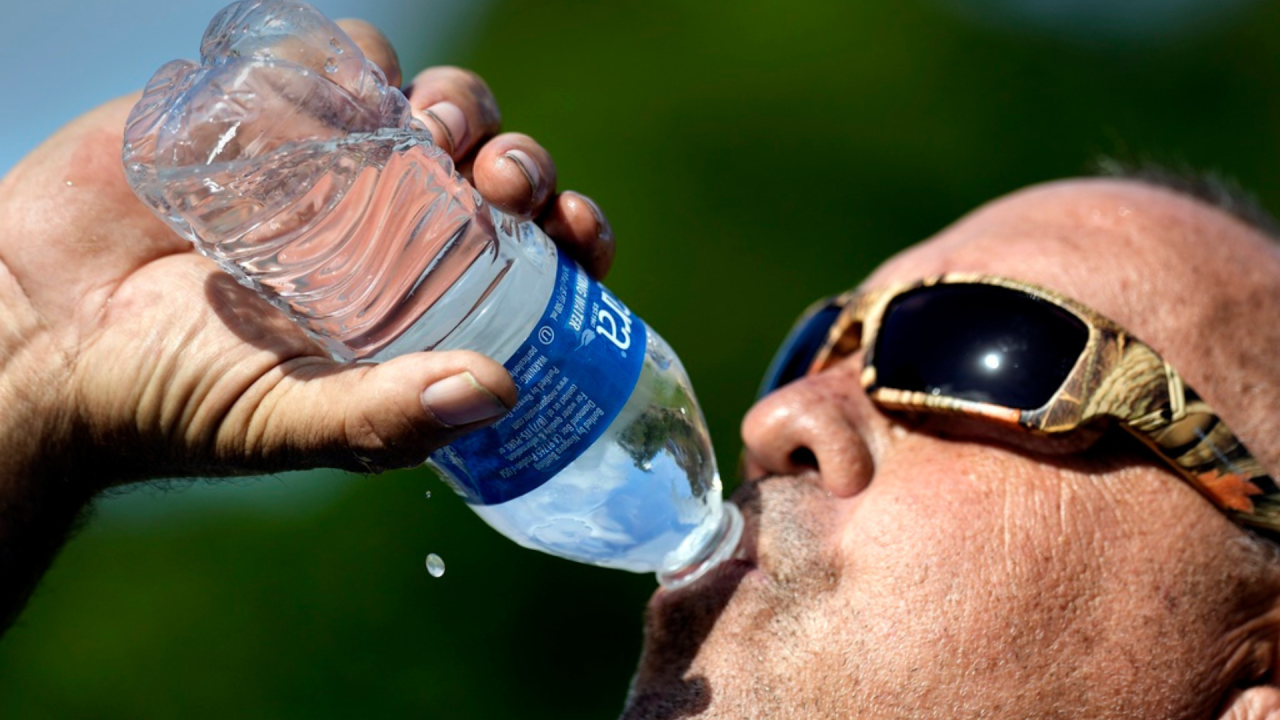  A man drinking water from a bottle.