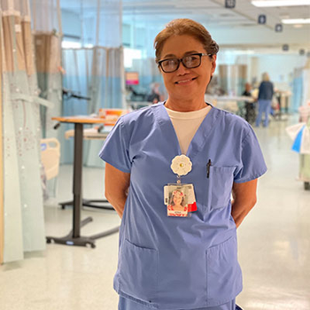 Nurse Edna, smiling and wearing scrubs, stands proudly in the hospital.
