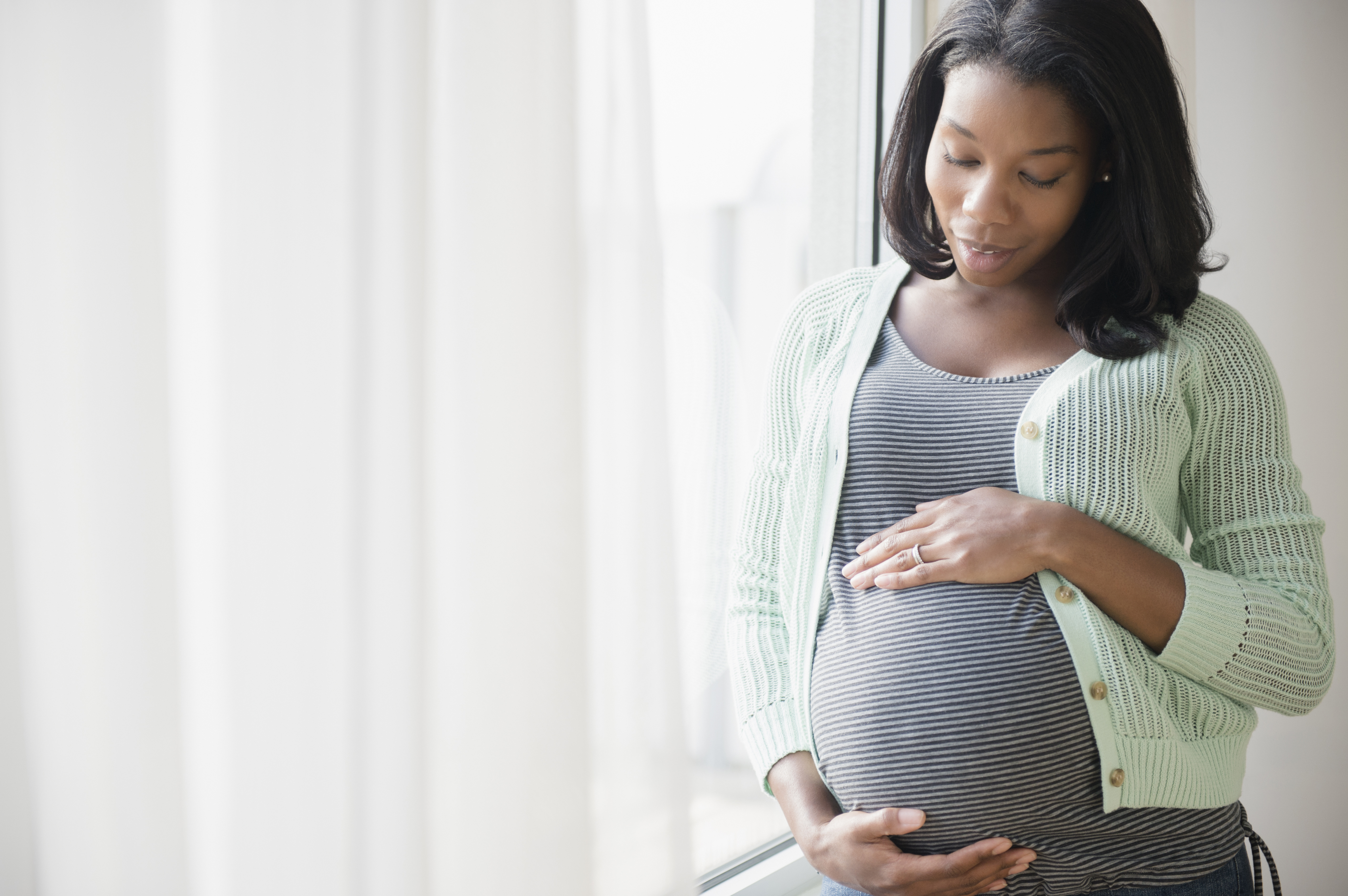 Pregnant woman looking down at stomach.