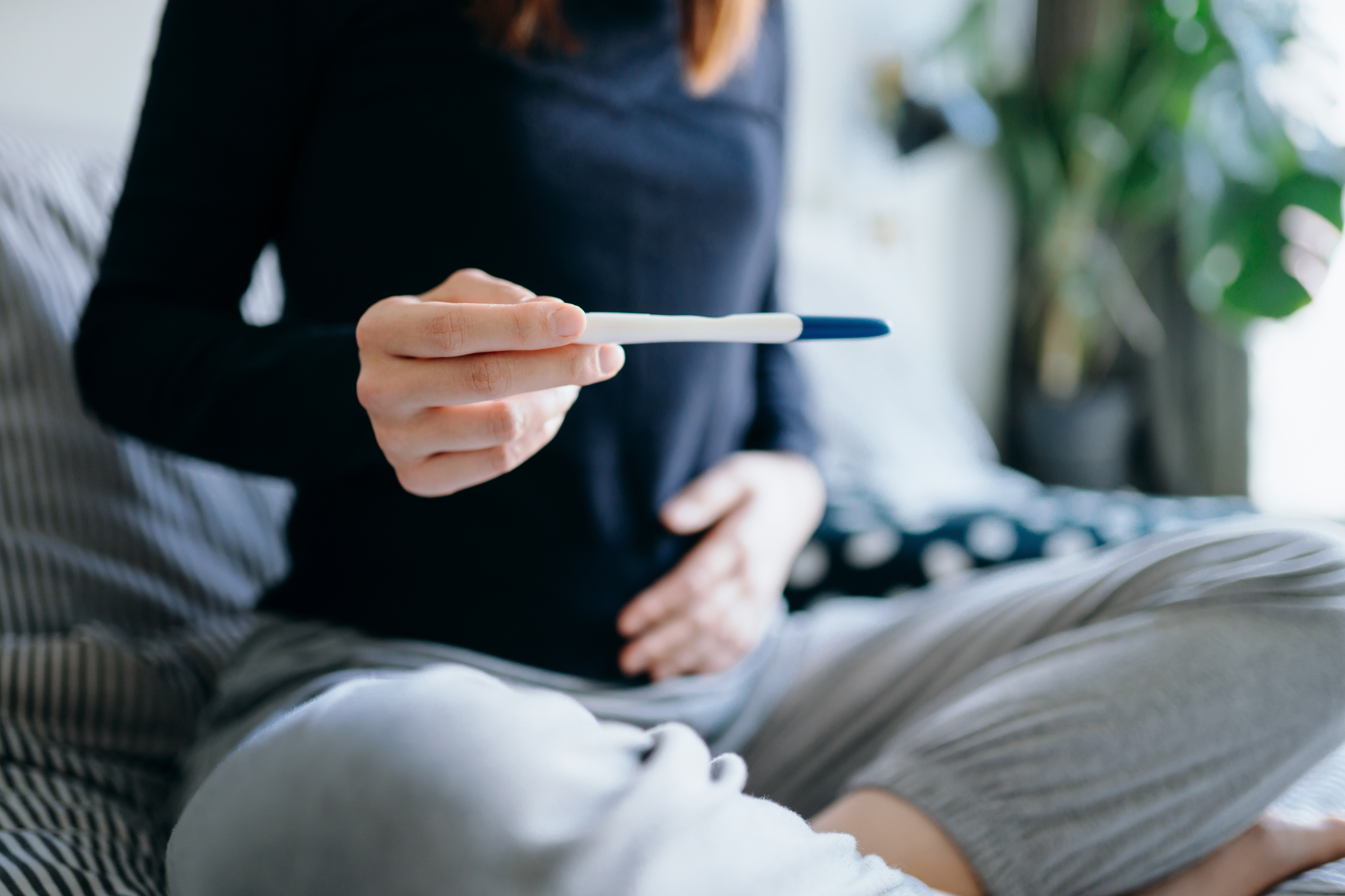 Woman holding her stomach while looking at a pregnancy test.