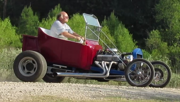 A man sitting in a classic red car.