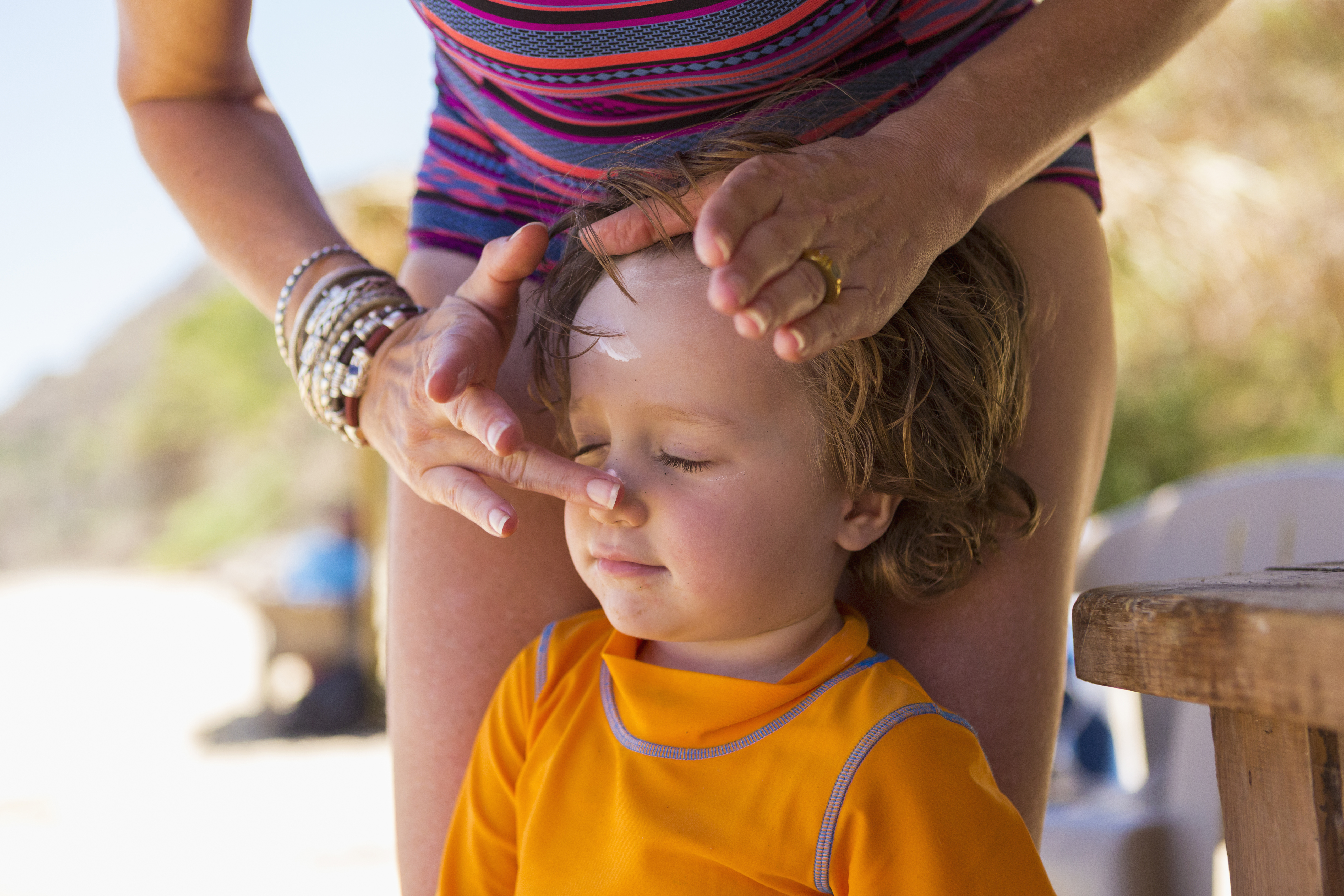 A child is having sunscreen applied to their face.