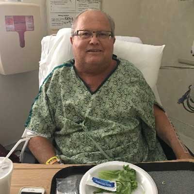 Kelly Zeh seated in a chair, alert and comfortable, several days after heart surgery.