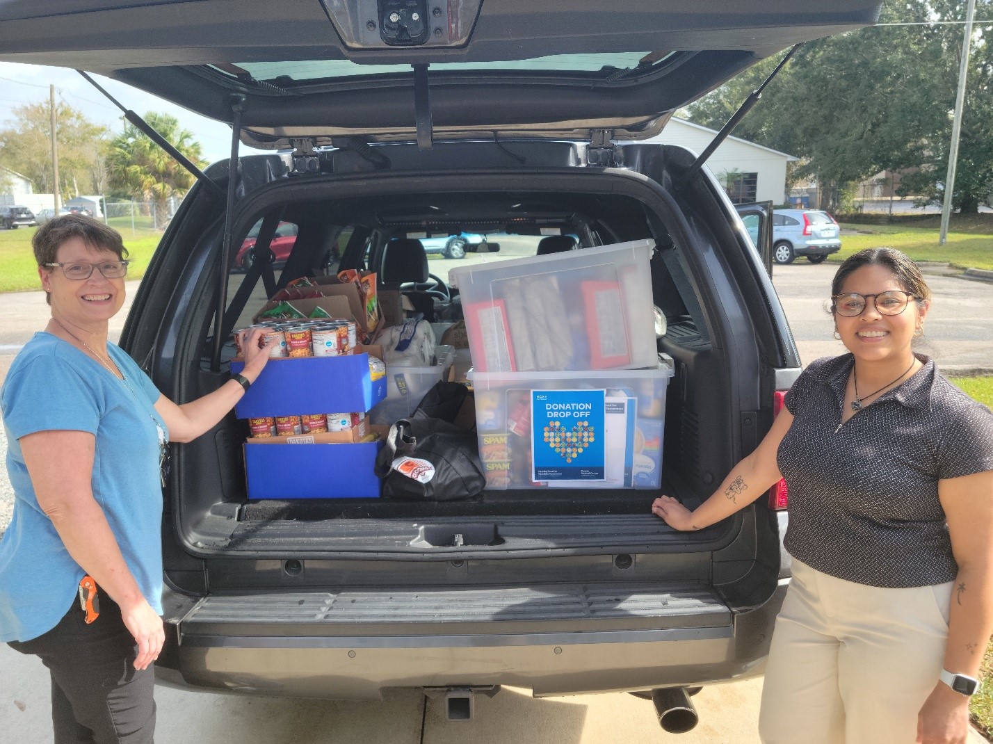 Tee Watters, supervisor, Engineering and Plant Operations at Oviedo Medical Center and Gabrielle Espinet, special events coordinator at HOPE Helps, with food pantry donations collected by colleagues at Oviedo Medical Center.