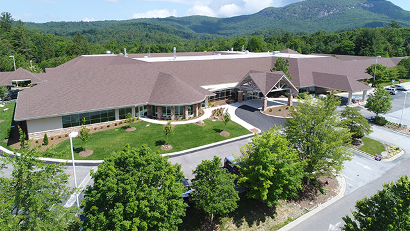 Exterior of the Highlands-Cashiers Hospital main entrance on summer day with mountains in the background.