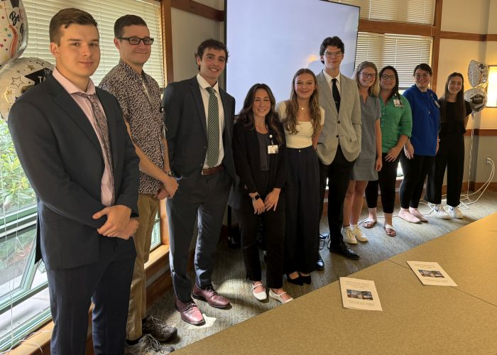 Portsmith Regional Hospital interns pose in a line along a windowsill in a conference room.