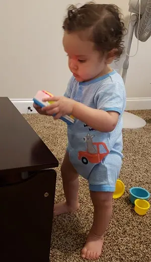 Enzio Rivera-Perez in a onesie playing with a light-up toy.