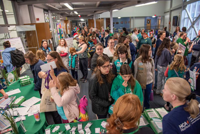 Brownie and Girl Scouts and their parents sitting at check–in in the lobby.