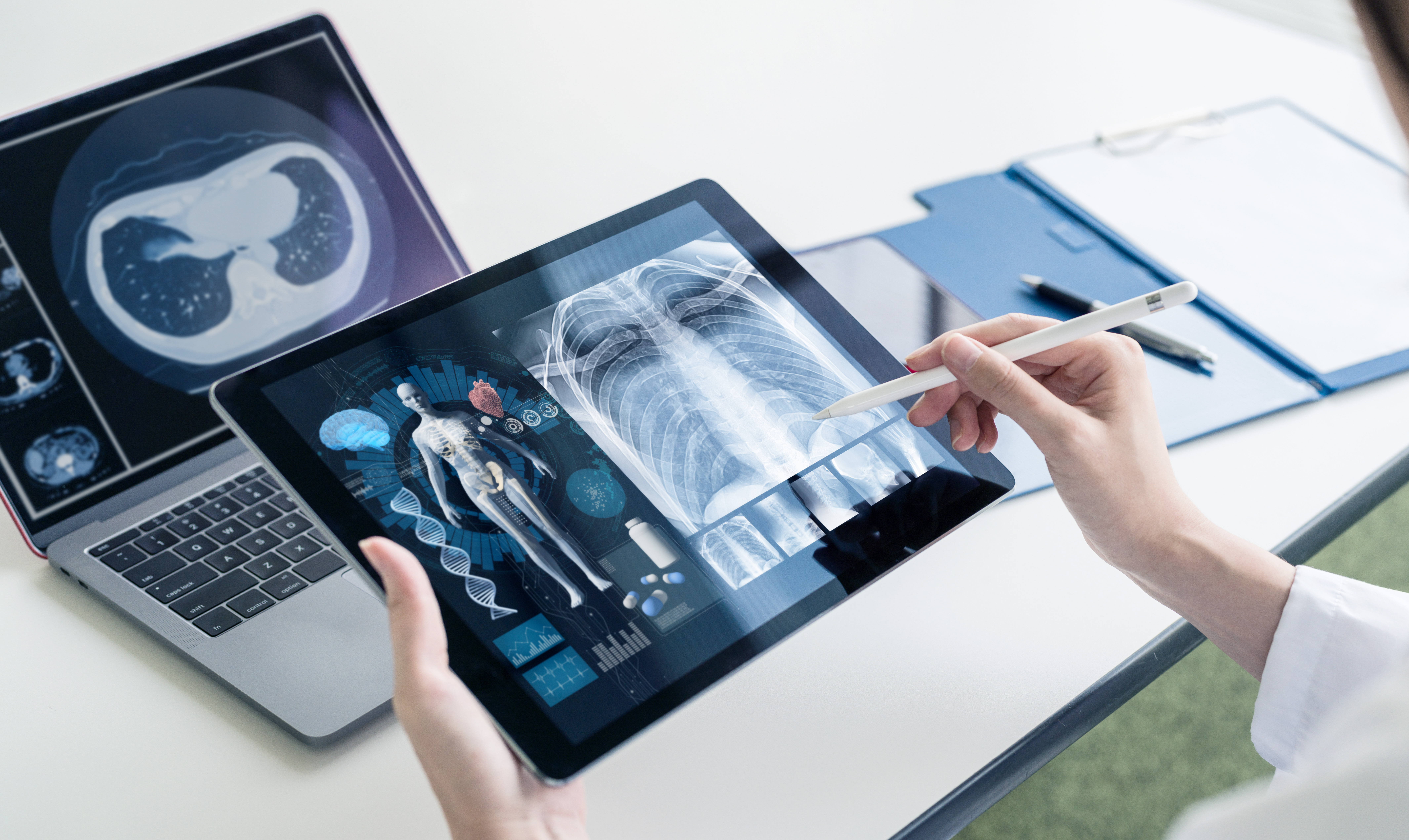 physician hands holding a digital tablet with images of a skeleton and an x-ray chest