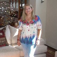 Debbie wearing white pants and a white top.
