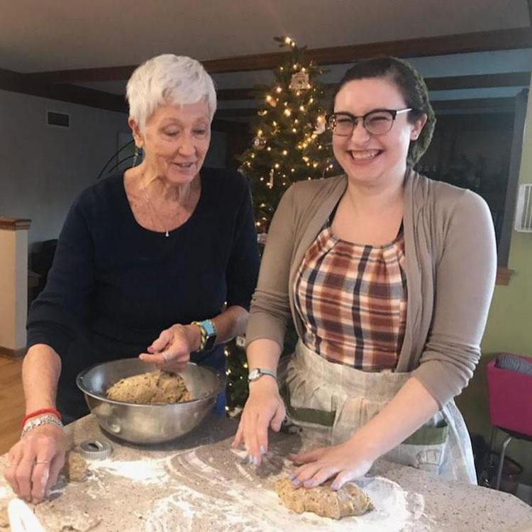 Zona and her family member smile while baking bread together.