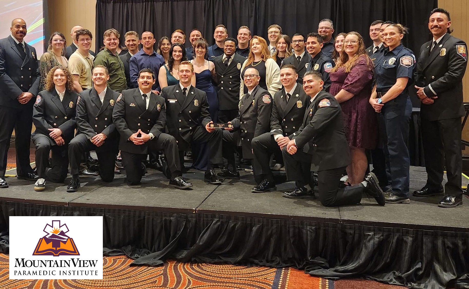 Graduates pose for a photo on a stage, with MountainView Parametic Institute logo on the bottom left.