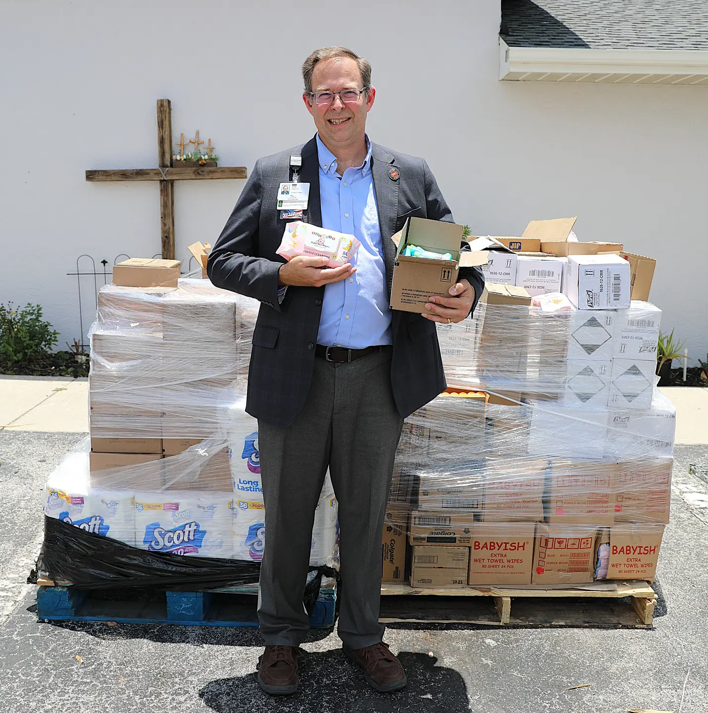 Adrian French smiling and posing for a picture, while holding hygiene items for donation.