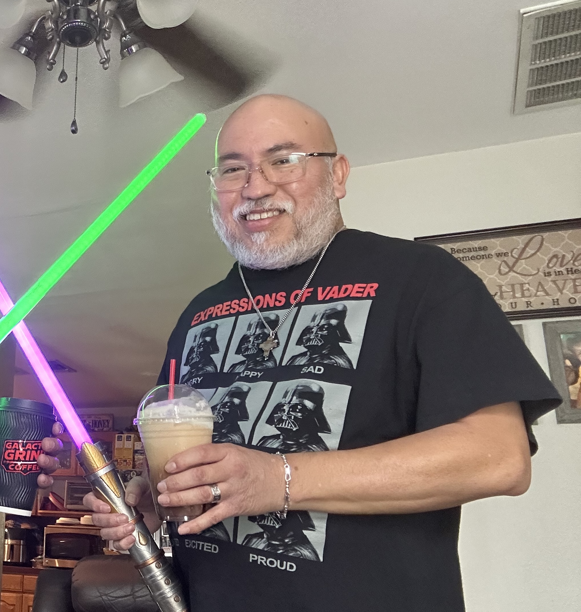 Carlos Tristan standing in a room holding a drink and a light saber
