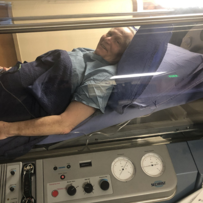 Patrick Murphy smiling from inside his hyperbaric chamber.