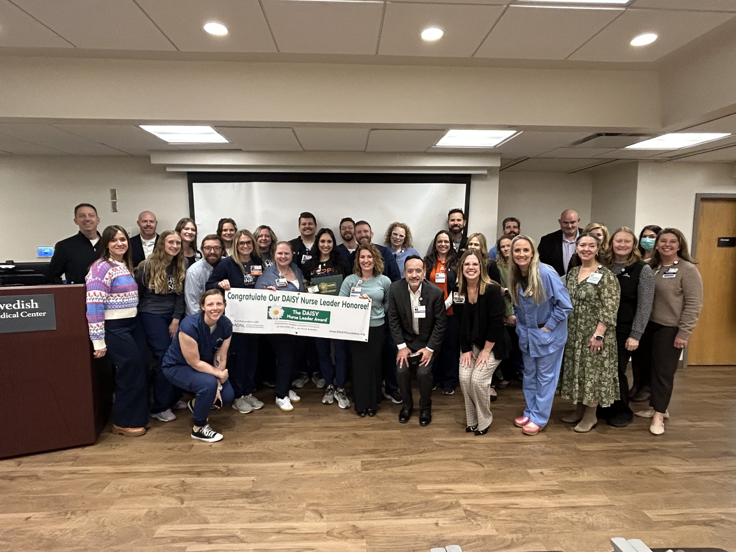 Shanaya Sharpe and her leadership team hold a banner congratulating her for being a daisy award honoree.
