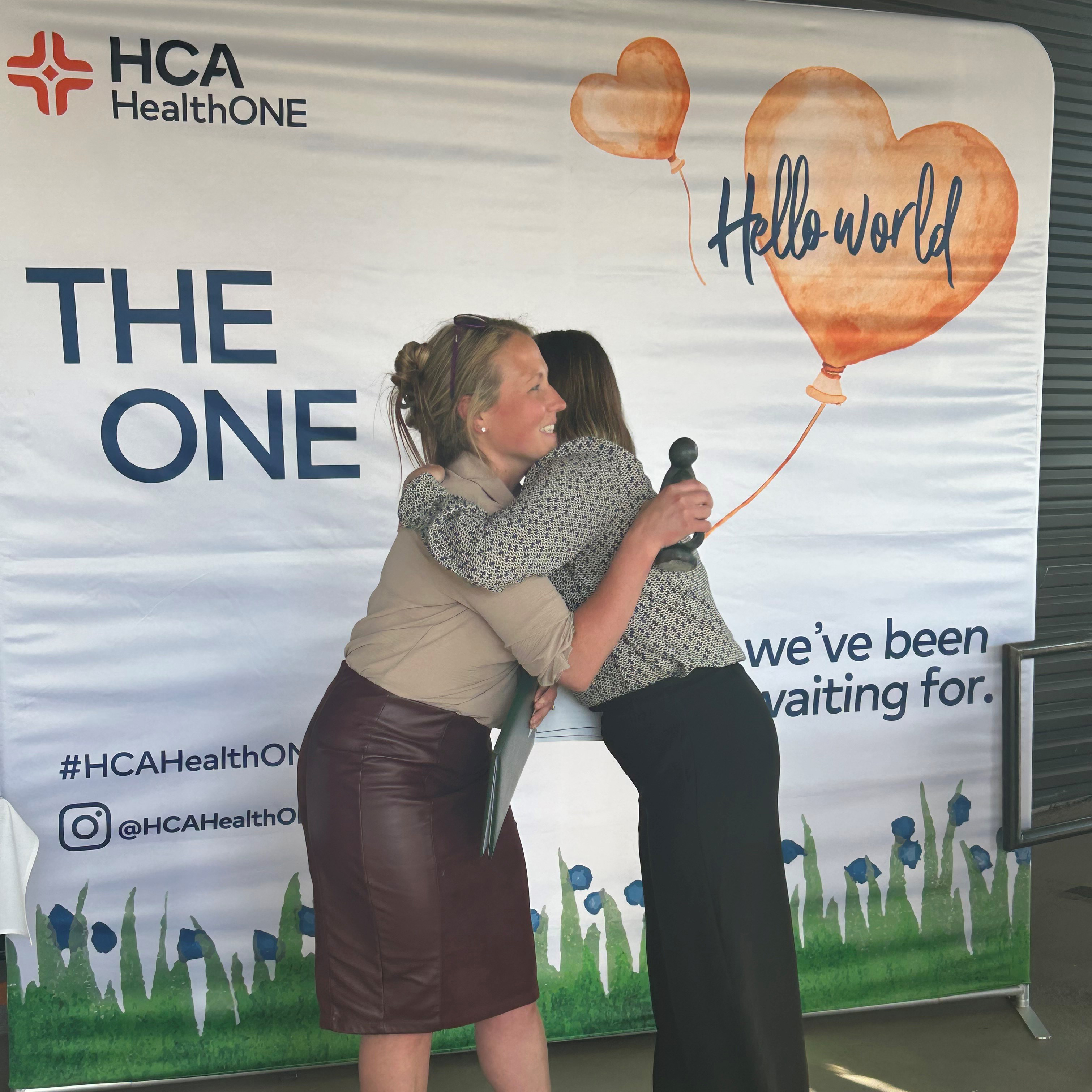 Taylor Myers recieving her DAISY award and a hug.