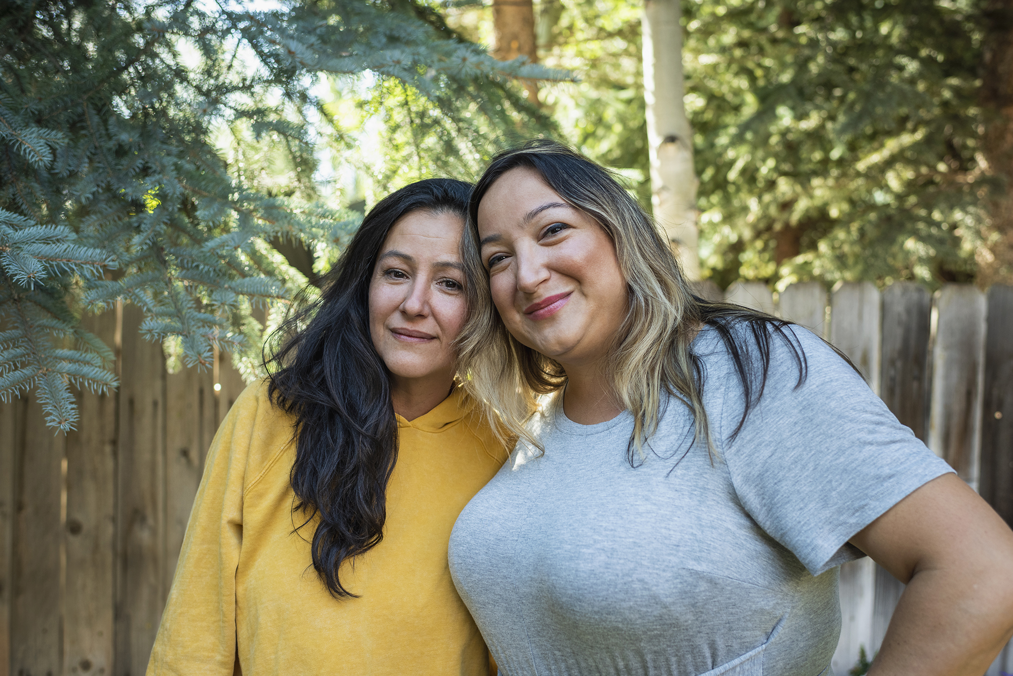Two women are embracing and smiling outdoors