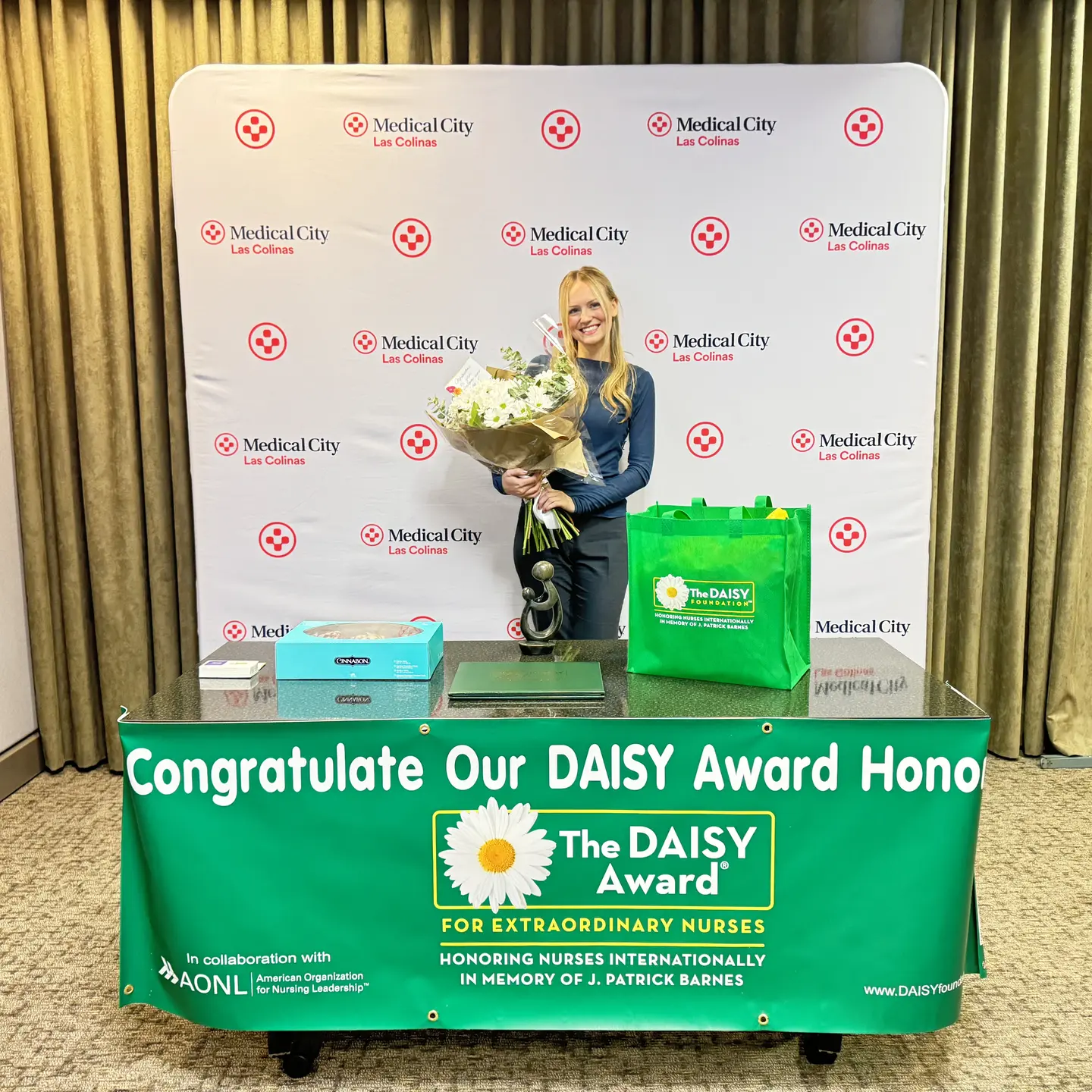 nurse Madi Wood with flowers. table with award and cinnamon rolls
