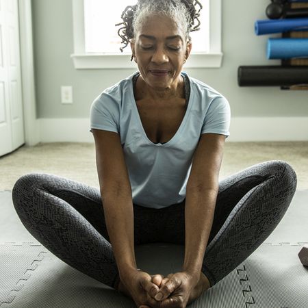 A woman stretching her inner thighs, eyes closed in relaxation, finding peace in the gentle release of tension.