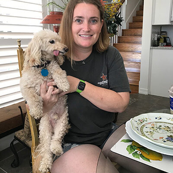 Mackenzie Mitchell holding a dog at a dinner table.