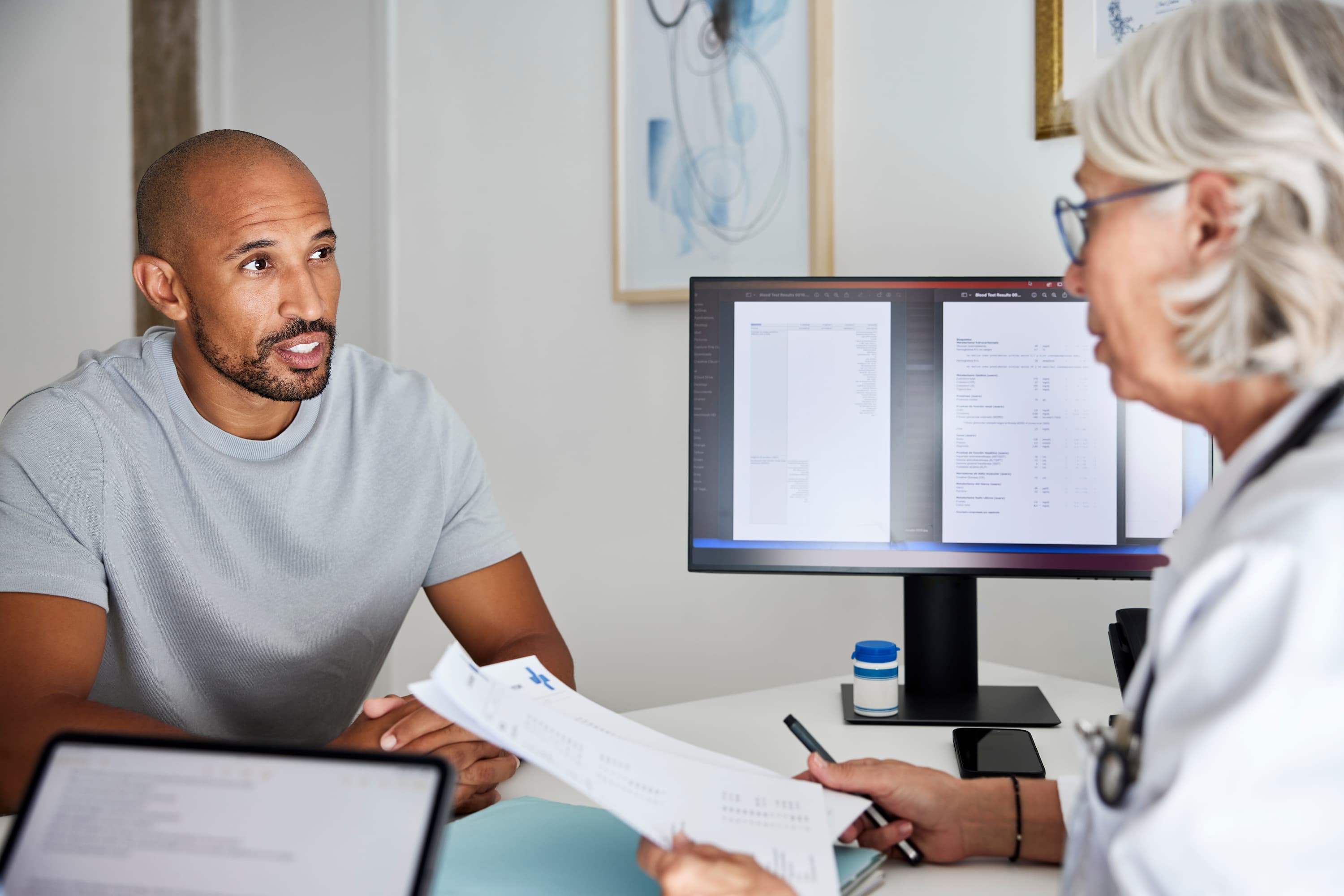 Man speaking with a doctor during a preventive health appointment, reviewing screening results in a medical office.