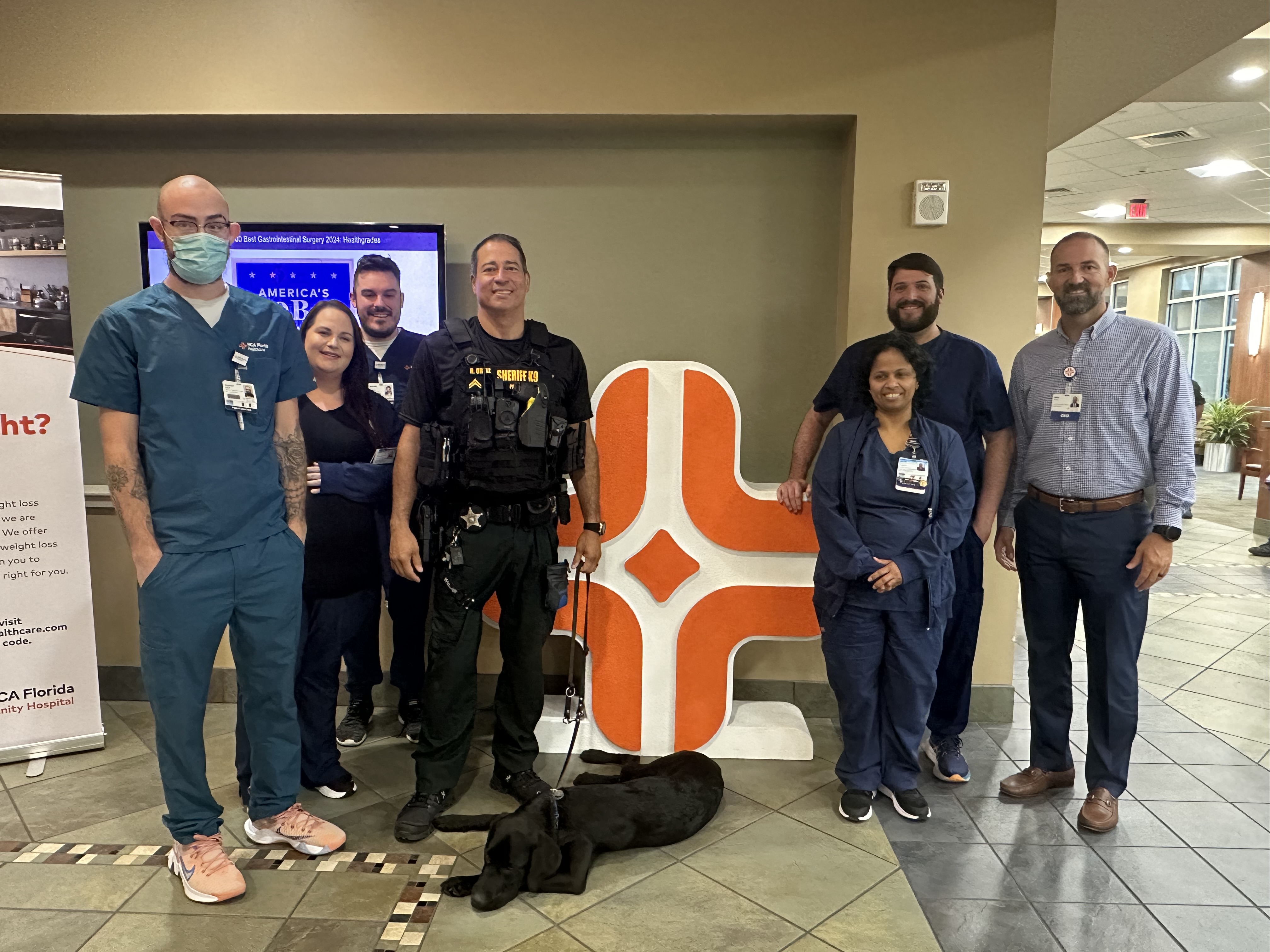Corporal Ortiz, Pasco County Sheriff Department, Mike Irvin, CEO HCA Florida Trinity Hospital and colleagues from the 5th floor who submitted the winning name pose with Milo.