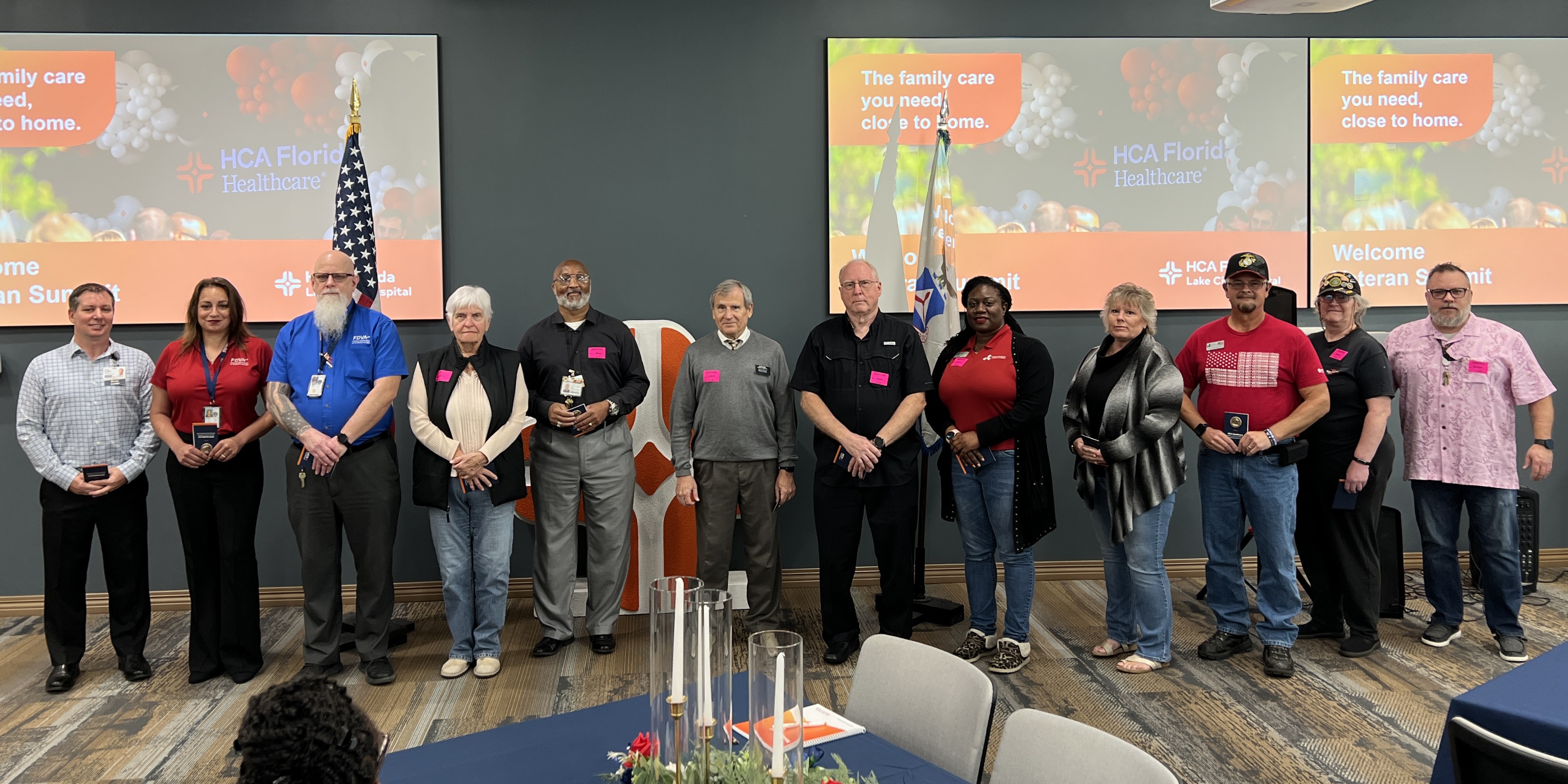 Twelve veterans standing alongside each other in a large conference room.