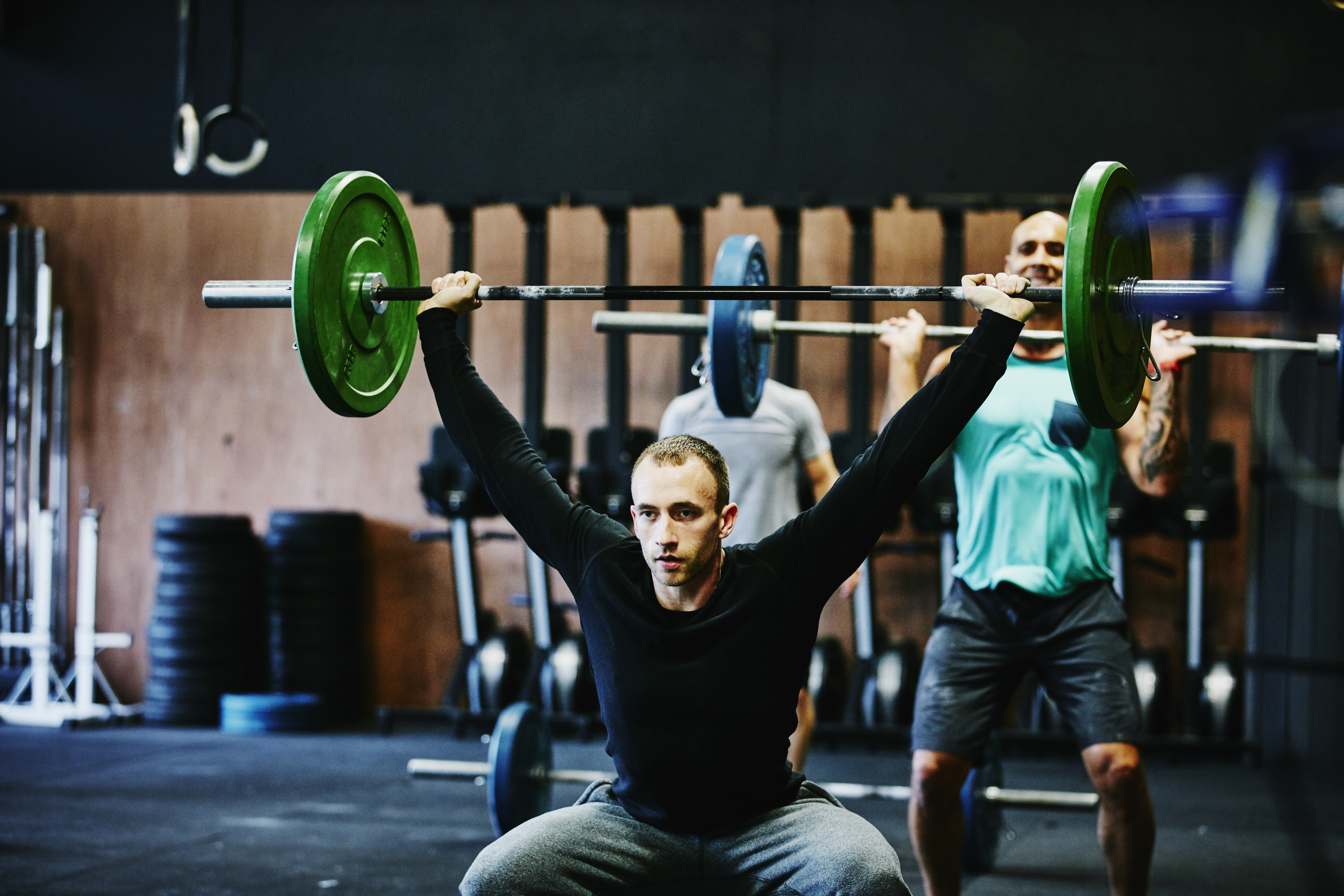 Man doing squats with barbell overhead.